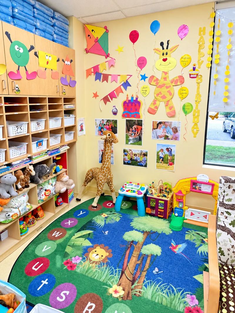An infant and toddler room with a birthday wall, family photo display and a jungle alphabet rug